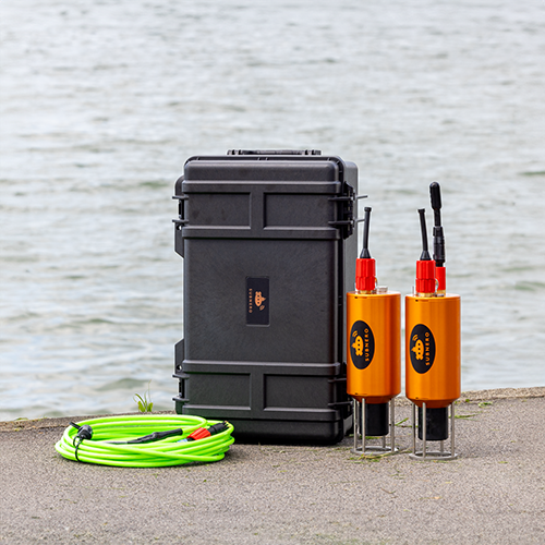 Subnero deployment kit including subsea cables, transport case, and two M25M Series acoustic smart modems set up at a waterside location